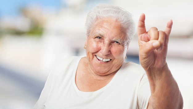 A mulher idosa que faz chifres com as mãos