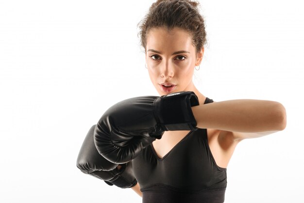 A mulher moreno encaracolado concentrada da aptidão treina em luvas de boxe
