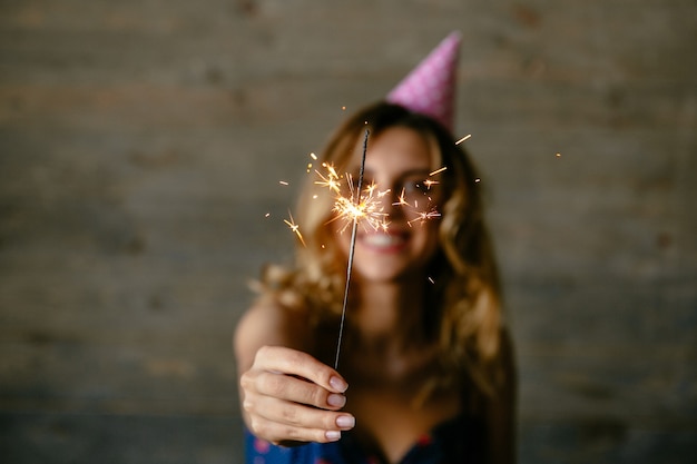 Foto grátis a mulher nova feliz prende a luz de bengal focalizada e comemora o feriado