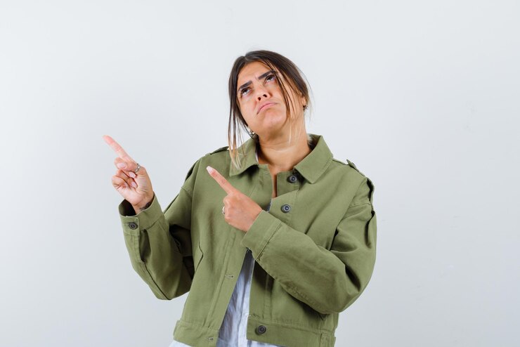 Foto grátis a mulher olhando para cima está apontando para a esquerda com os dedos no fundo branco