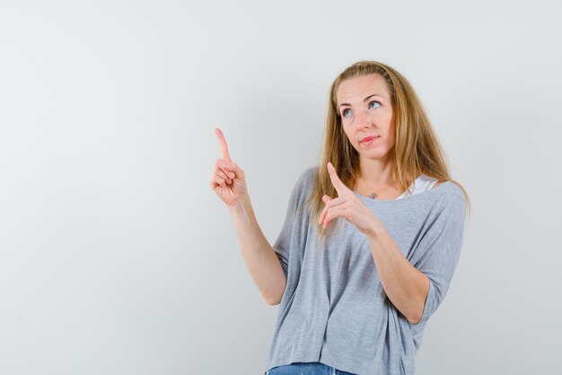 A mulher olhando para cima está apontando para cima com os dedos no fundo branco