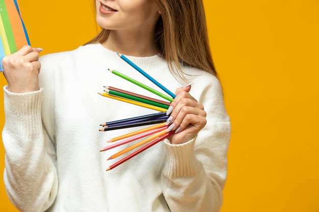 A mulher prende lápis coloridos e bloco de notas colorido