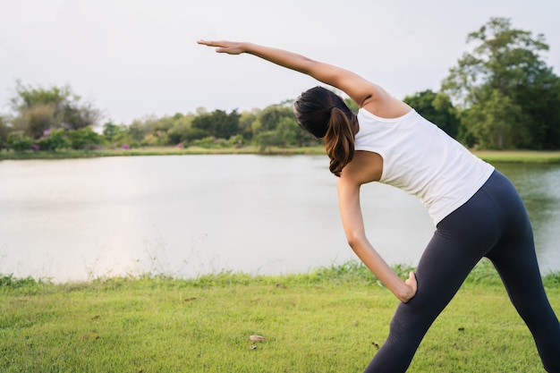 A mulher saudável do corredor asiático novo aquece o corpo que estica antes do exercício e da ioga