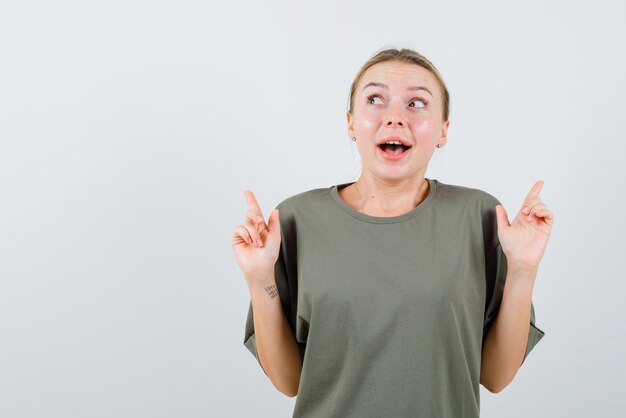 A mulher sorridente está apontando para cima com os dedos no fundo branco