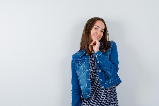 A mulher sorridente está colocando a mão no queixo no fundo branco