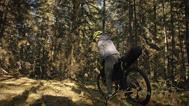 A mulher viaja em ciclismo de terreno misto com bike bikepacking. a viagem do viajante com malas de bicicleta. parque da floresta mágica.