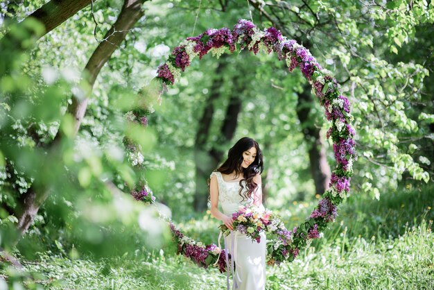 A noiva com cabelo largo e escuro fica em um grande círculo de lilás