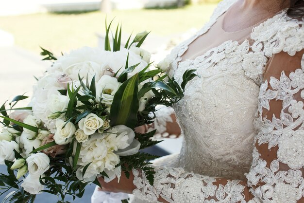 A noiva morena deslumbrante mantém rico bouquet de casamento branco