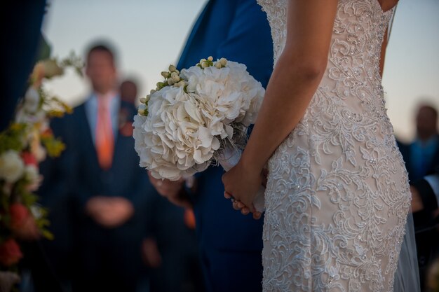 A noiva no vestido com cristais fica com o buquê nas mãos