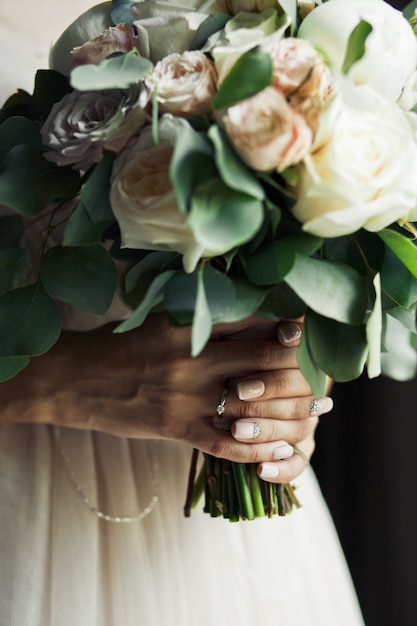 A noiva segura o bouquet de casamento de peônias em tons pastel