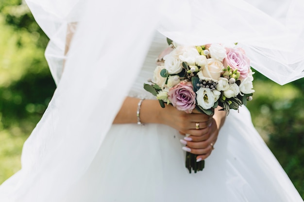 A noiva tem um buquê de casamento nas mãos