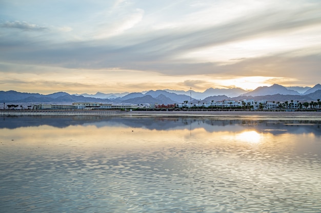 A paisagem do céu é refletida no mar com figuras solitárias ao longe.