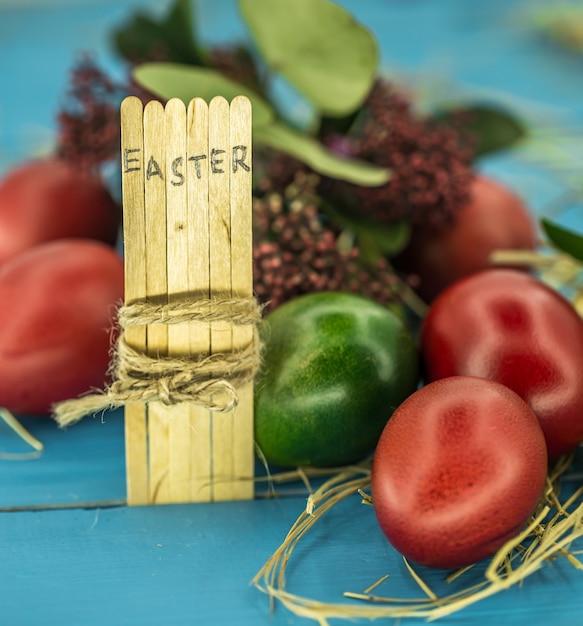 Foto grátis a palavra páscoa no texto do bloco conceitual em palitos de madeira, lindos ovos festivos com verduras