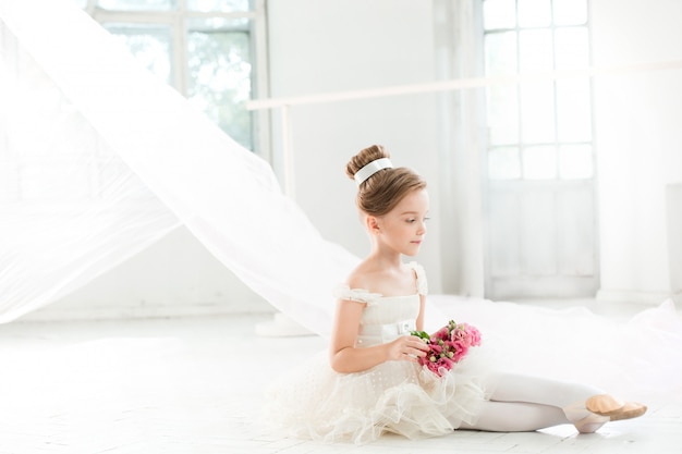 A pequena bailarina com tutu branco na sala de aula de ballet