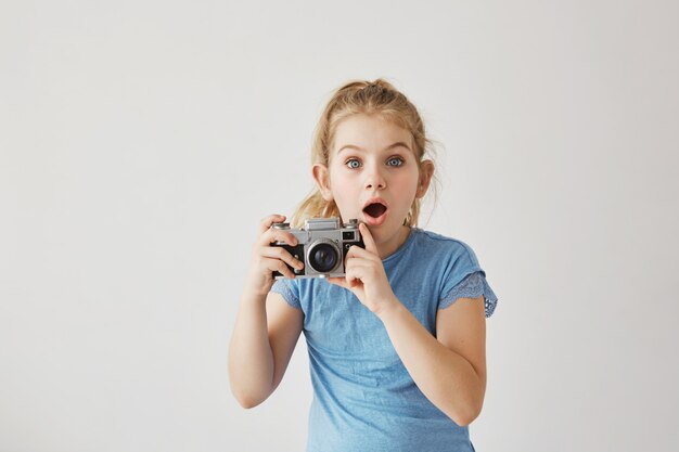 A pequena garota loira de olhos azuis estava tirando uma foto de família dos pais com uma câmera de filme quando o pai escorregou e caiu. Criança olhando assustada que o pai se machucar.