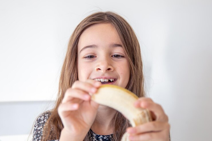 Foto grátis a rapariga está a comer uma banana. conceito de emoções.
