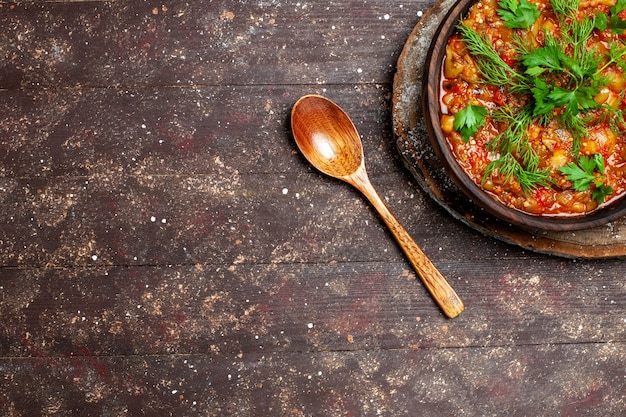A saborosa refeição cozinhada da vista de cima consiste em vegetais fatiados e verduras em uma refeição marrom de mesa, molho de sopa