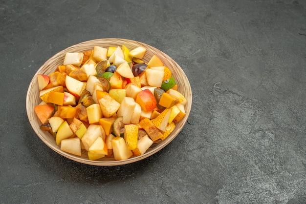 A saborosa salada de frutas da vista frontal consiste em frutas frescas em frutas do chão cinza, muitas delas frescas