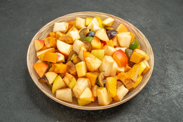 A saborosa salada de frutas da vista frontal consiste em frutas frescas na mesa cinza muitas frutas frescas