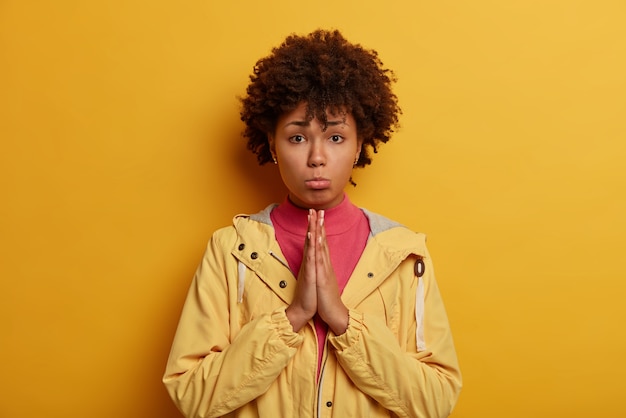 Foto grátis a senhora afro-americana de pele escura implorando franze o lábio inferior e mantém as mãos em gesto de oração, vai chorar quando precisa desesperadamente de ajuda, pede desculpas