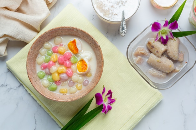 Foto grátis a sobremesa tailandesa chamou bolas de bualoy em colheres com leite de coco quente e folhas de pandan para aumentar a delícia.