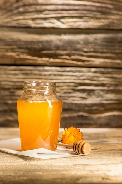 A tigela com mel na mesa de madeira. o banco de mel fica perto da colher de pau