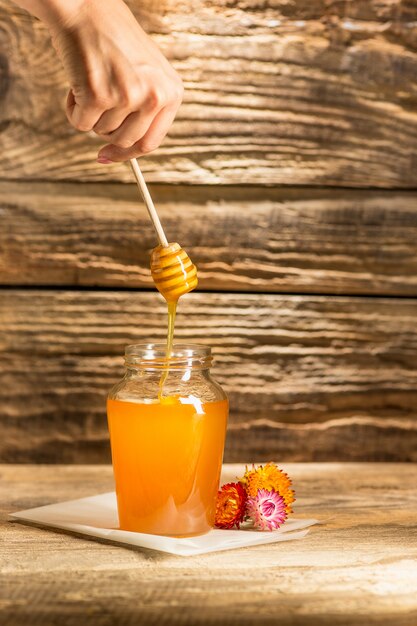 A tigela com mel na mesa de madeira. O banco de mel fica perto da colher de pau