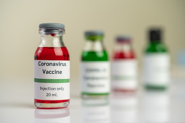 A vacina contra o covid-19 está em vermelho e verde em garrafas colocadas no chão.