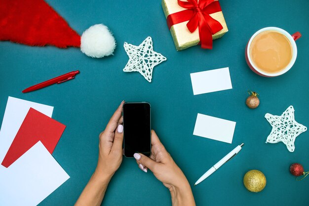 A vista superior das mãos femininas com telefone e decorações de Natal