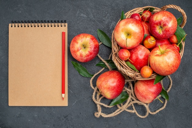 A visualização em close-up de cima frutifica as apetitosas cerejas e maçãs na cesta de lápis