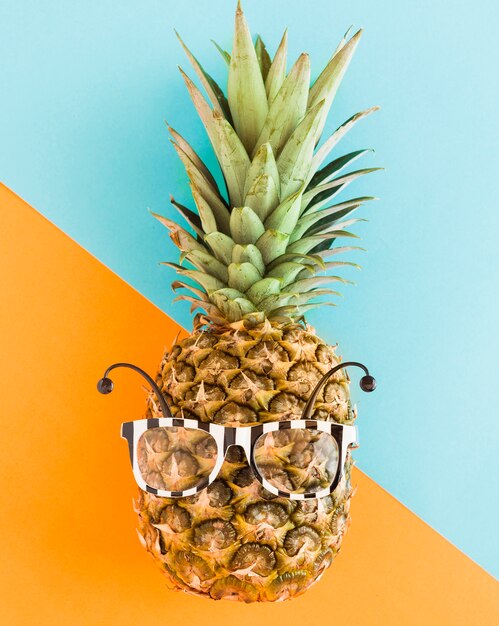 Abacaxi na moda em óculos de sol em plano de fundo multicolorido