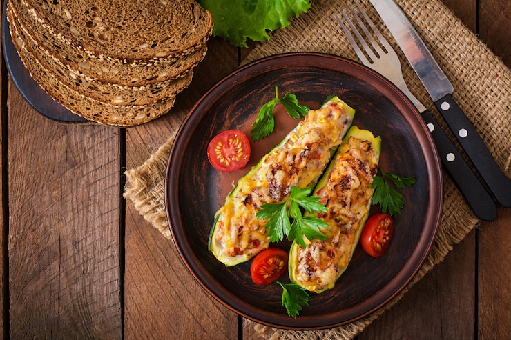 Foto grátis abobrinha recheada com frango, tomate e cebola com crosta de queijo