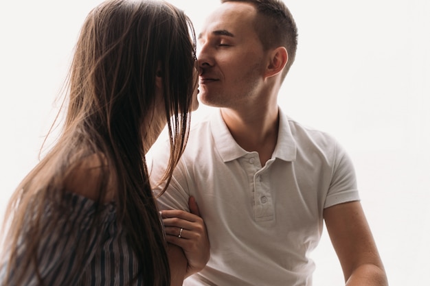 Abraços quentes do homem novo e da mulher que estão no quarto moderno acolhedor