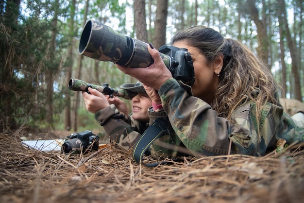 Absorvida mãe e filho tirando fotos na floresta. Família com câmeras modernas no chão, usando câmera e binóculos. Parentalidade, família, conceito de lazer