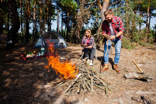 Acampamento de casal fazendo fogo na floresta