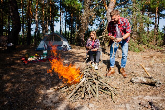 Acampamento de casal fazendo fogo na floresta