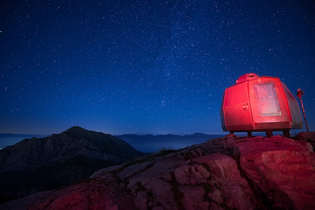 Acampamento iluminado vermelho nas montanhas altas sob um lindo céu estrelado