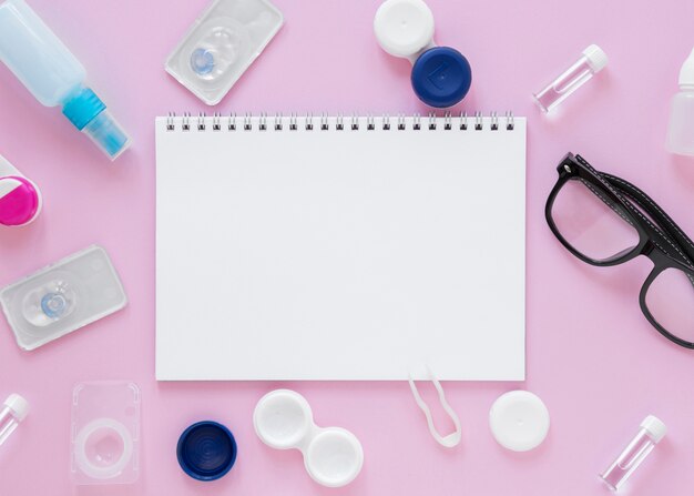 Acessórios de cuidados dos olhos em fundo rosa com maquete de notebook