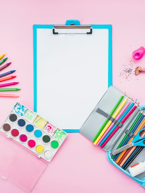 Acessórios de desenho coloridos e prancheta sobre o fundo rosa