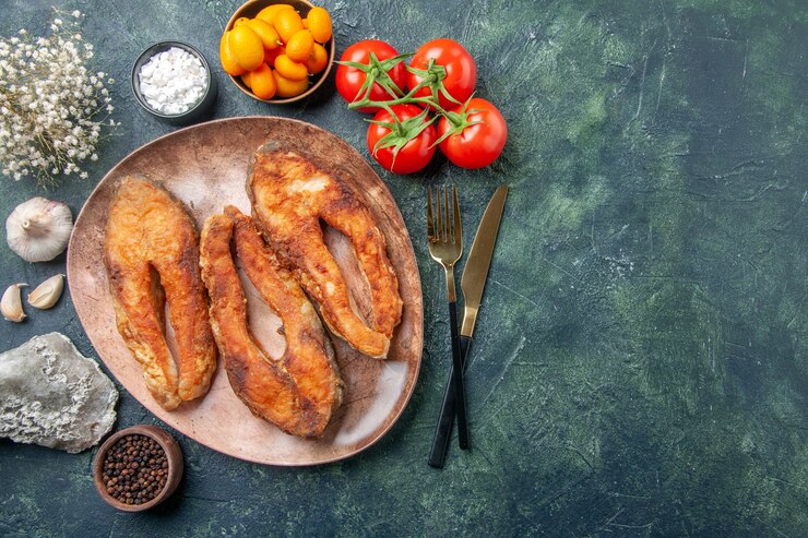 Foto grátis acima, a vista de um delicioso peixe frito em um prato marrom e talheres define alimentos com especiarias em uma mesa de mistura de cores com espaço livre