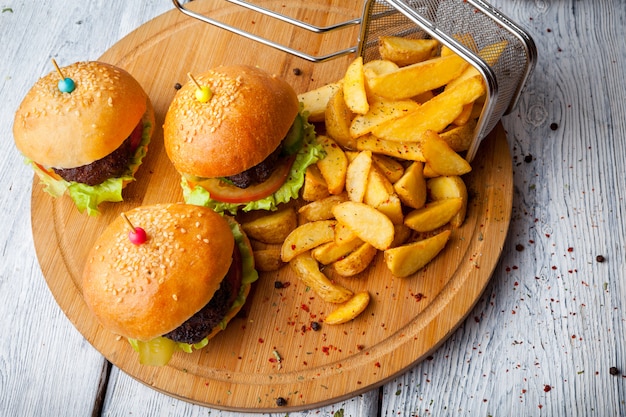 Acima de hambúrguer com batatas fritas e cesta de fritura na placa de alimentos