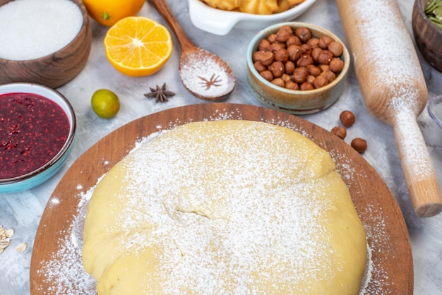 Foto grátis acima vista da farinha de pastelaria crua na placa redonda compota de avelãs fatias de limão ralador em fundo cinza
