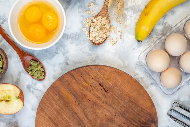 Acima vista da placa redonda de madeira e ingredientes para a alimentação saudável em mesa azul branca
