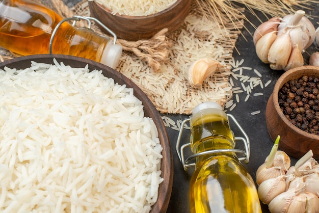 Foto grátis acima vista de tigelas marrons de arroz longo perfeitas em garrafas de óleo caídas de toalha de cor nua alhos pimentas em fundo escuro