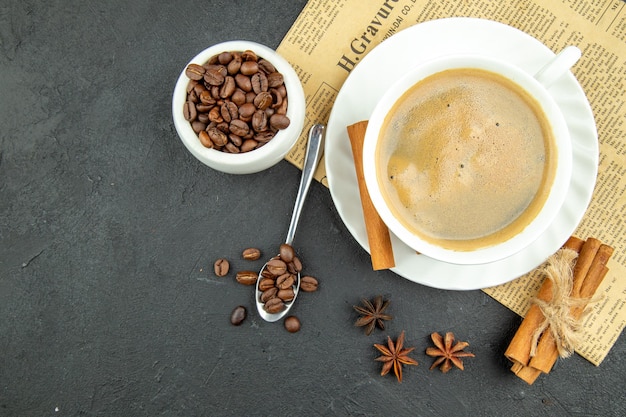 Acima vista de uma xícara de café delicioso e limas de canela em backgorund escuro