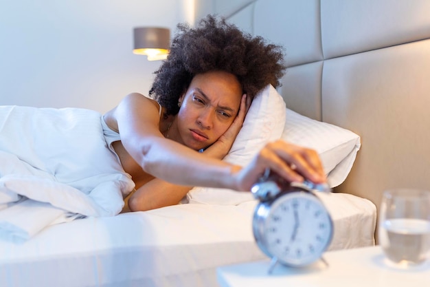 Foto grátis acorde de uma garota adormecida parando o despertador na cama de manhã mulher dormindo e acorde para desligar o despertador de manhã