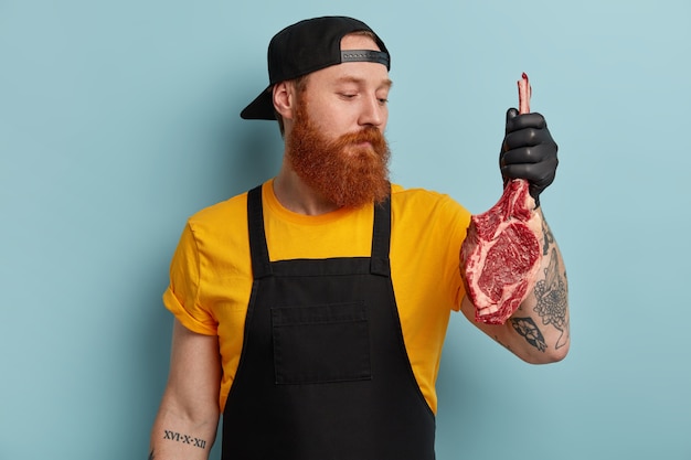 Açougueiro com barba ruiva segurando carne