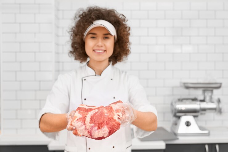 Foto grátis açougueiro feminino demonstrando carne no supermercado.