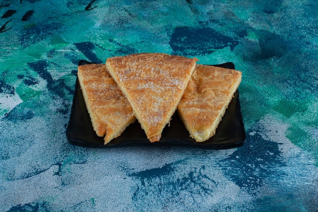 Açúcar em pó sobre o pão em uma placa de madeira, na mesa de mármore.