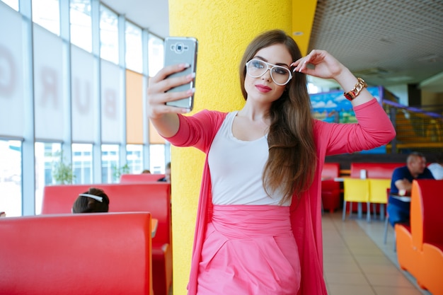 Adolescente à moda com os vidros brancos posando para foto